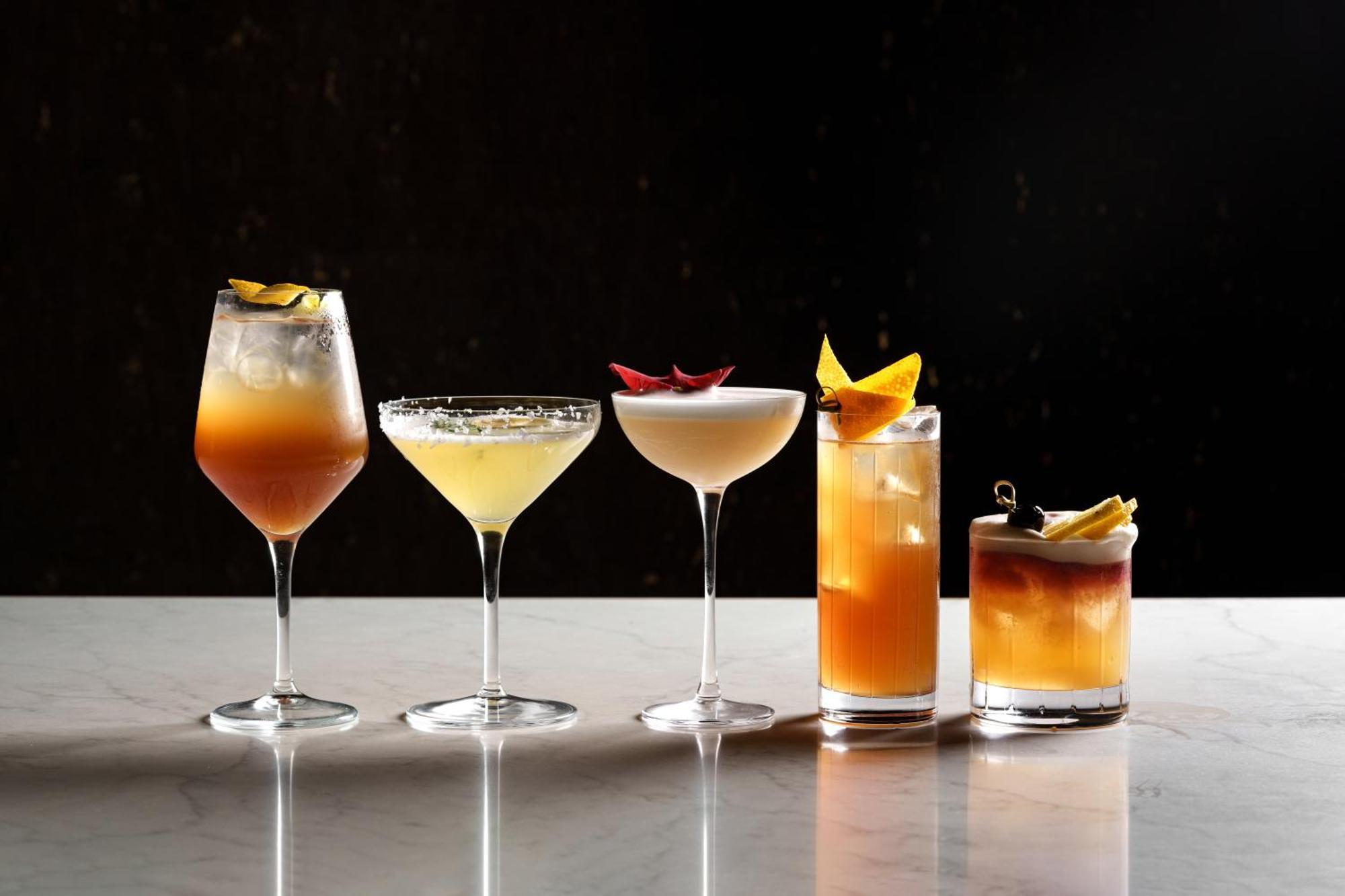 Middle Eight - Covent Garden - Preferred Hotels And Resorts Лондон Экстерьер фото The photo features a selection of five different cocktails lined up on a marble surface. Each drink is served in a distinct glass, showcasing a variety of colors and garnishes. 

1. The first cocktail is in a large wine glass, with a gradient color f
