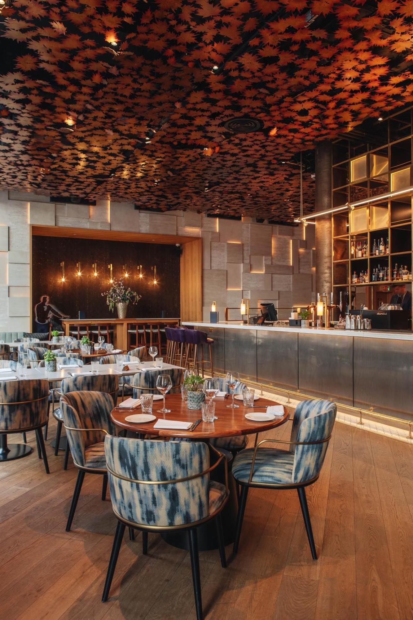 Middle Eight - Covent Garden - Preferred Hotels And Resorts Лондон Экстерьер фото The photo shows a stylish restaurant interior. There are round tables set with plates and glasses, surrounded by comfortable chairs. The bar area is sleek and modern, with a counter displaying various bottles. The lighting appears warm and inviting, 